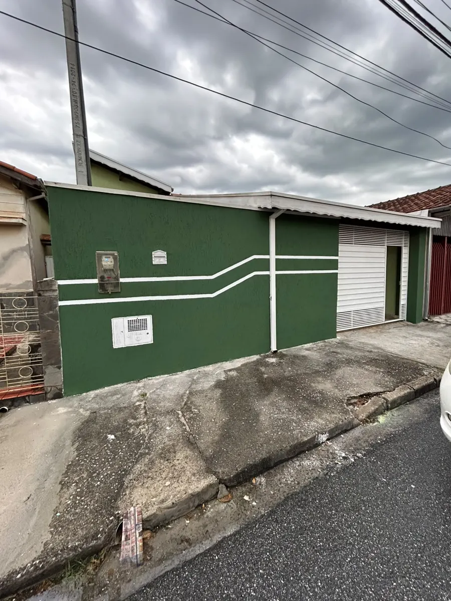 Muro e fachada residencial pintados em verde com faixas brancas decorativas
